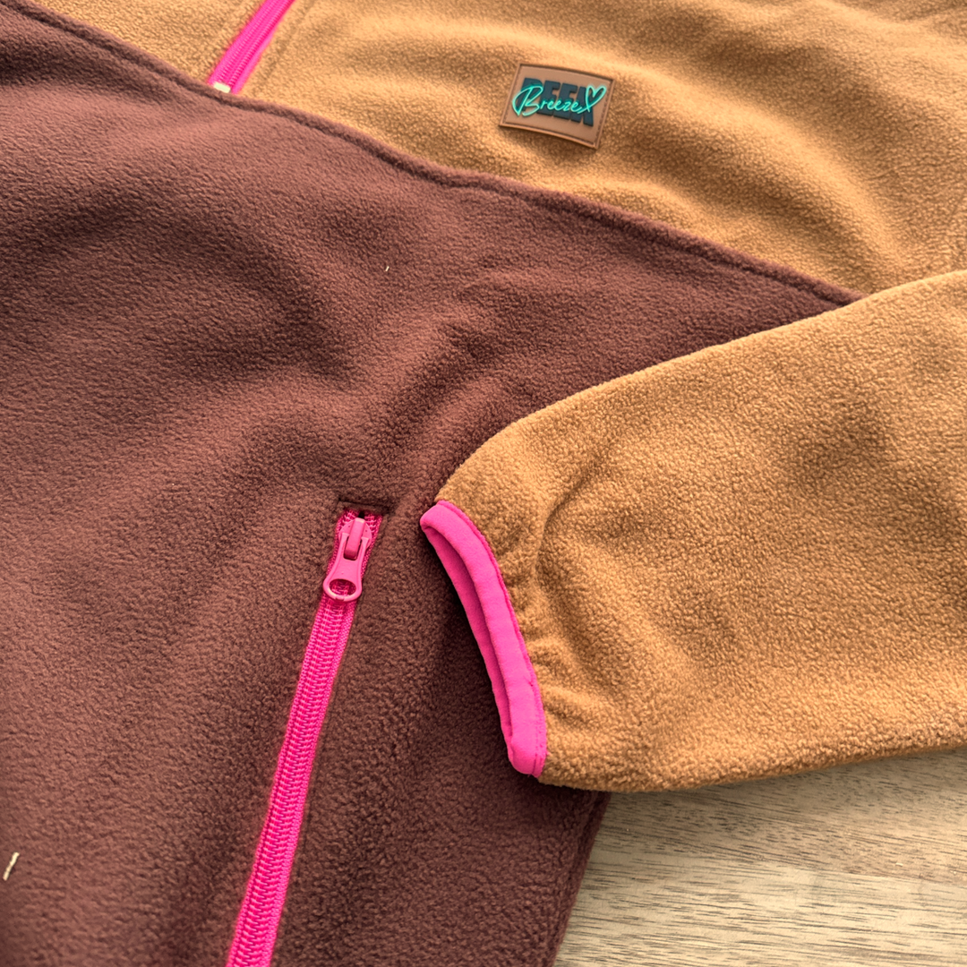 Gros plan de la poche zippée fuchsia du polar court Toffee Peek Breeze