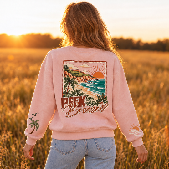 Vue de dos du Crewneck Coastal rose pâle Peek Breeze pour femme, avec grand imprimé tropical représentant une plage, des palmiers et un coucher de soleil.