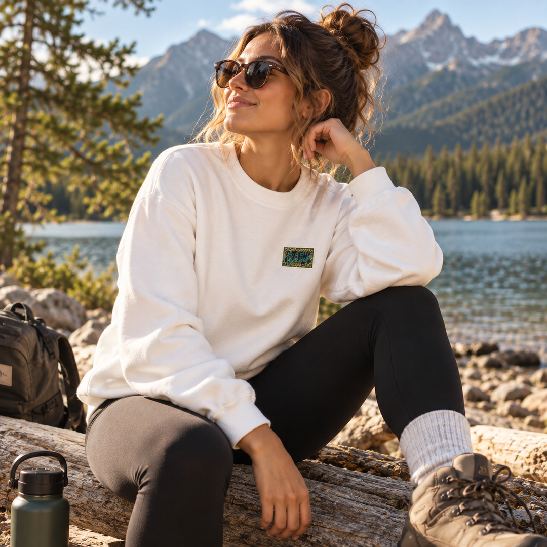 Femme portant le crewneck WILD blanc Peek Breeze en plein air près d’un lac en montagne