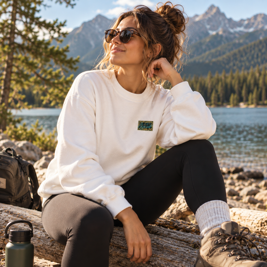 Femme portant le crewneck WILD blanc Peek Breeze en plein air près d’un lac en montagne
