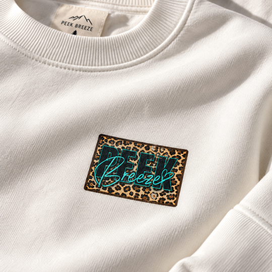 Détail du logo Peek Breeze imprimé motif léopard sur le crewneck WILD blanc