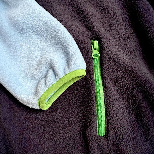 Détail de la poche latérale zippée de la robe polaire Seaside Peek Breeze, avec polar bleu marine, manche bleu pâle et finitions vert lime.