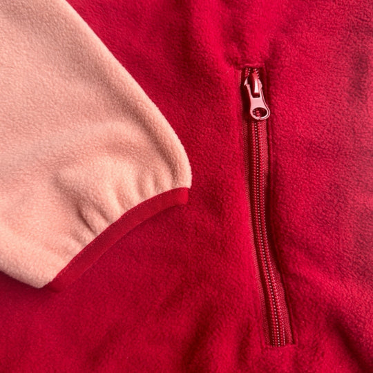 Gros plan d’une robe en polar Peek Breeze rouge foncé et rose pâle montrant la finition de la manche et la fermeture éclair de la poche latérale.