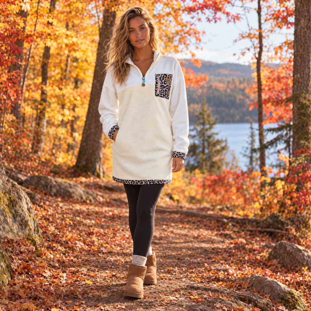 Femme blonde portant la robe polar Savana ivoire et léopard Peek Breeze, marchant dans un sentier en forêt à l’automne